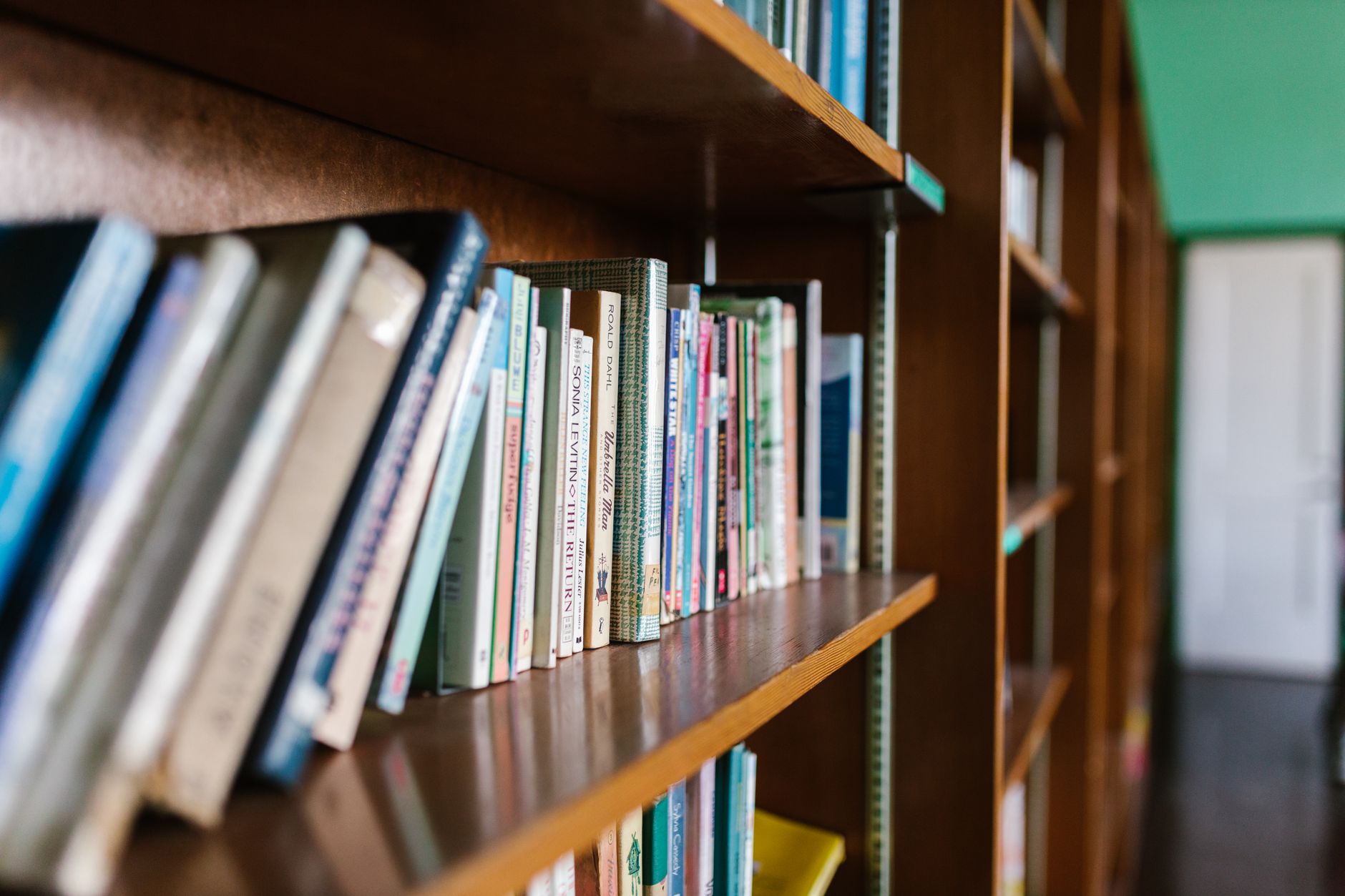 A wooden bookshelf filled with books in a cozy library setting, perfect for educational themes.